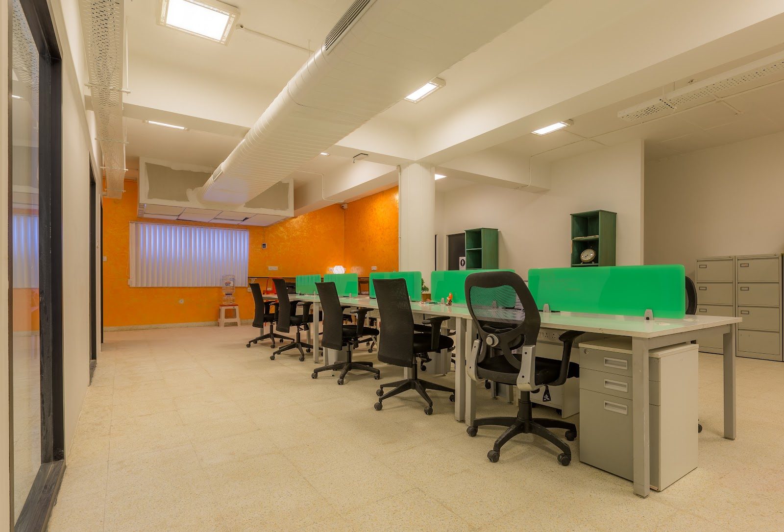 Open-plan workstations with green screens and daylight